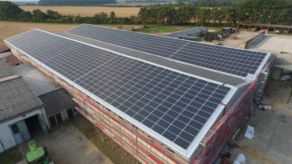 Große Produktions- und Lagerhalle mit einer umfangreichen Solaranlage auf dem Dach, Symbol für nachhaltige Energieerzeugung und moderne Infrastruktur.
